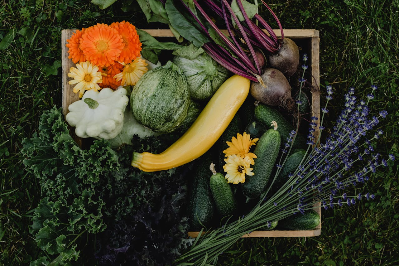 Assortment of fresh organic vegetables and colorful flowers in a box.
